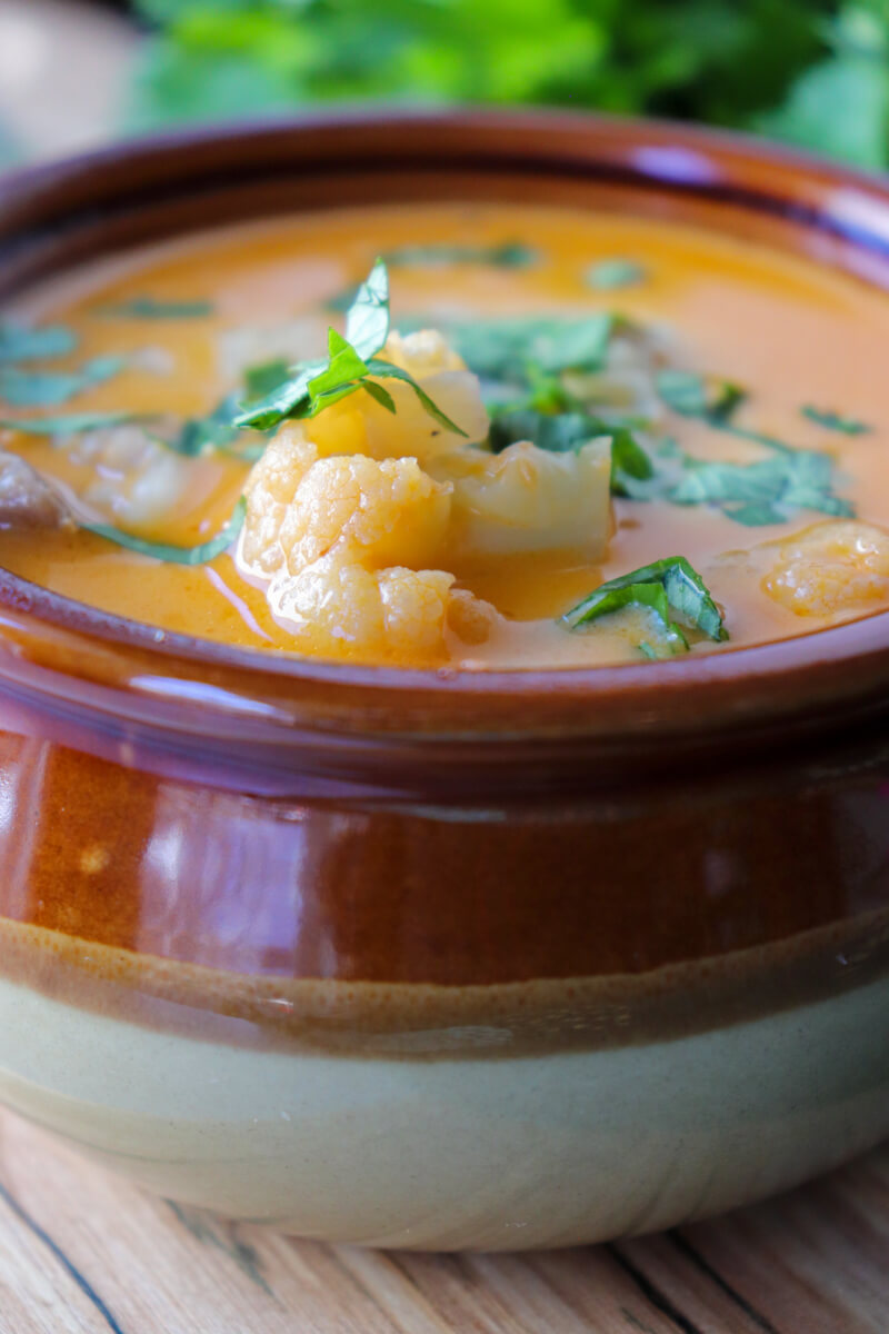 Front view of a brown ceramic bowl of keto white chicken chili with chopped cilantro.