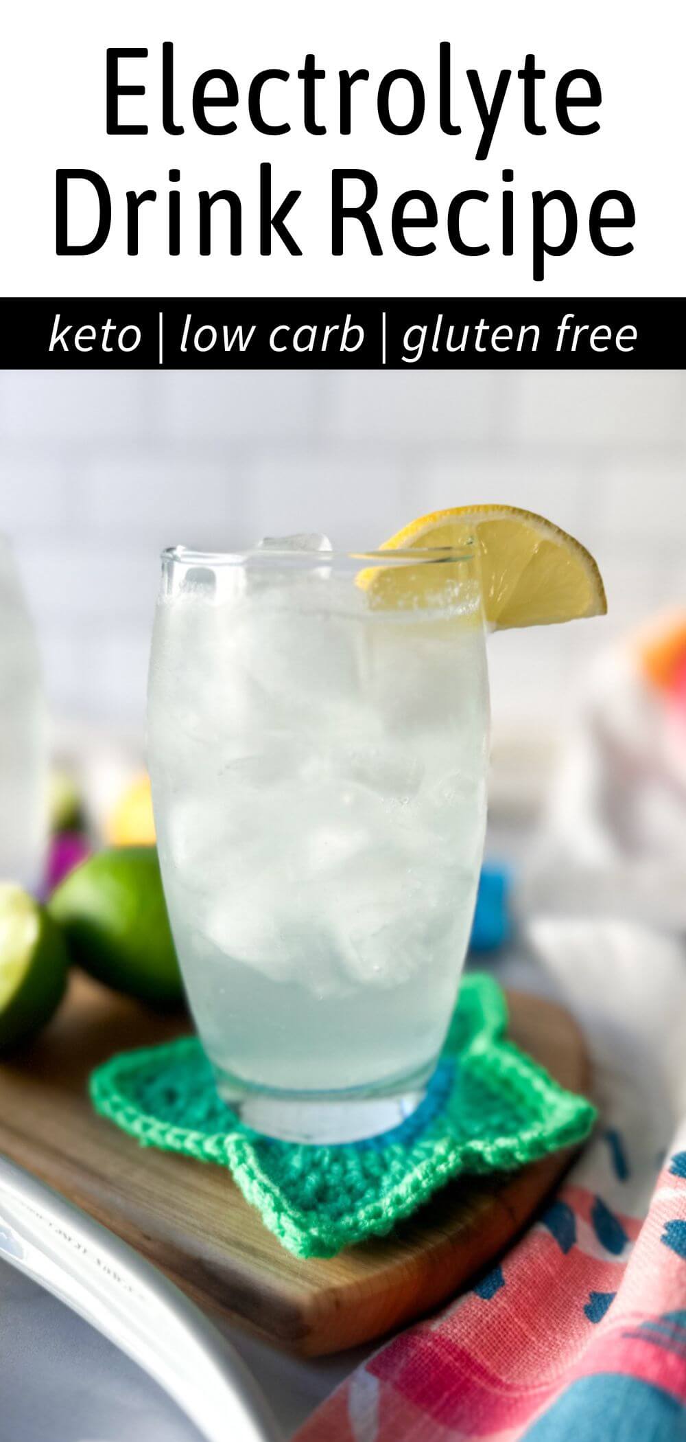 A clear glass filled with a low carb electrolyte drink, pale color, with ice and a lemon on the rim of the glass. Sitting on a wooden cutting board and crocheted green star coaster. Text overlay reads, "Electrolyte Drink Recipe, Keto, Low Carb, Gluten Free."