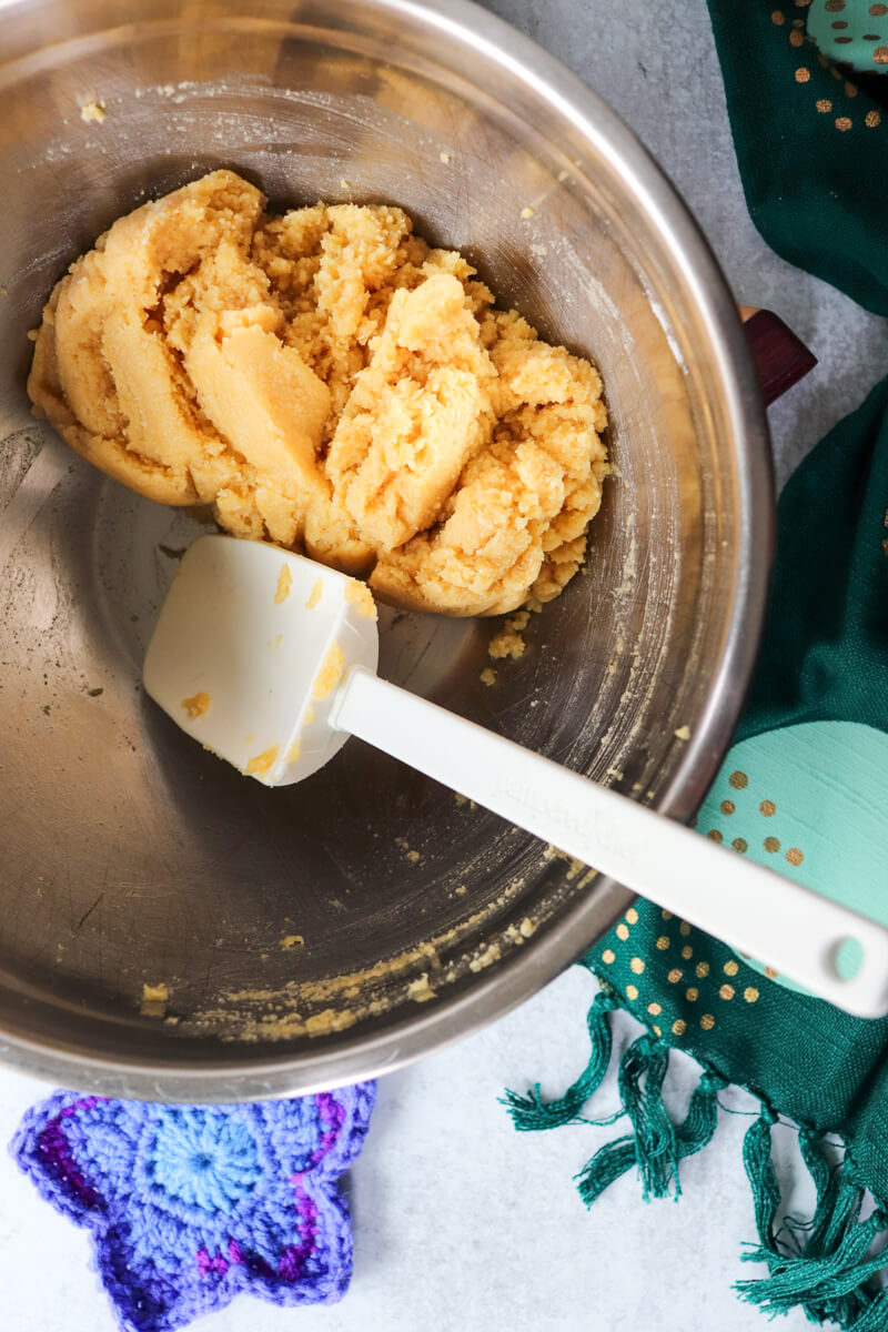 Overhead view of a metal bowl with low carb shortbread dough and a white spatula