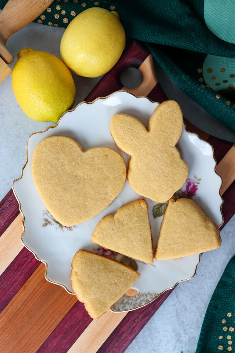 Overhead view of holiday themed cut out keto short bread cookies on a white plate, heart, rabbit, etc.
