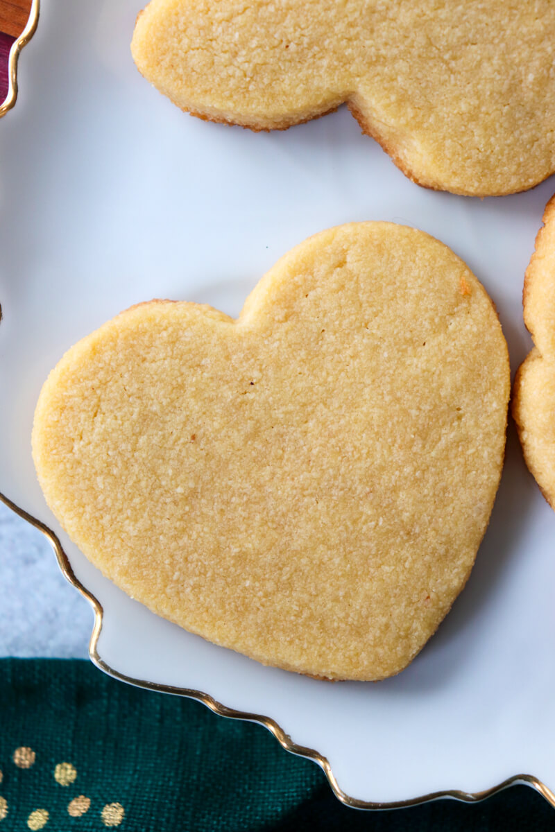 A low carb heart shaped shortbread cookie on a white plate with others around