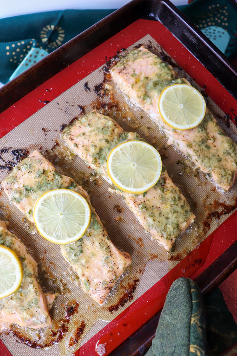 Overhead view of a pan of 4 servings of baked keto salmon on a silicone baking mat