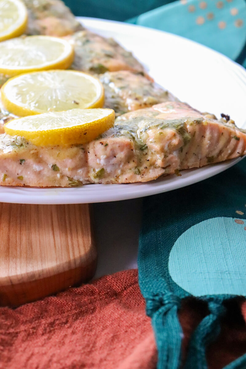 Front side closeup view of a white plate with 4 servings of baked salmon with lemon dijon sauce