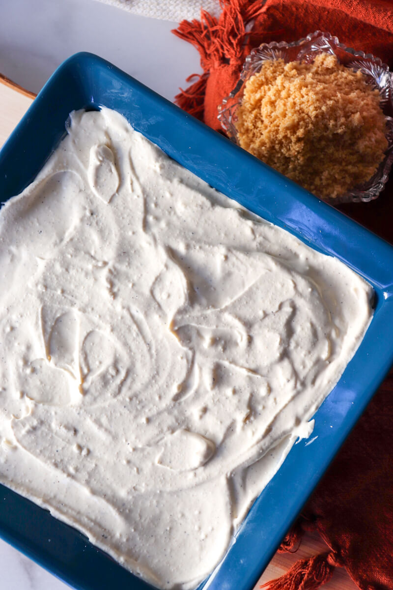 Overhead view of a blue casserole dish with low carb chicken cordon bleu casserole before the topping in put on, creamy sauce is visible