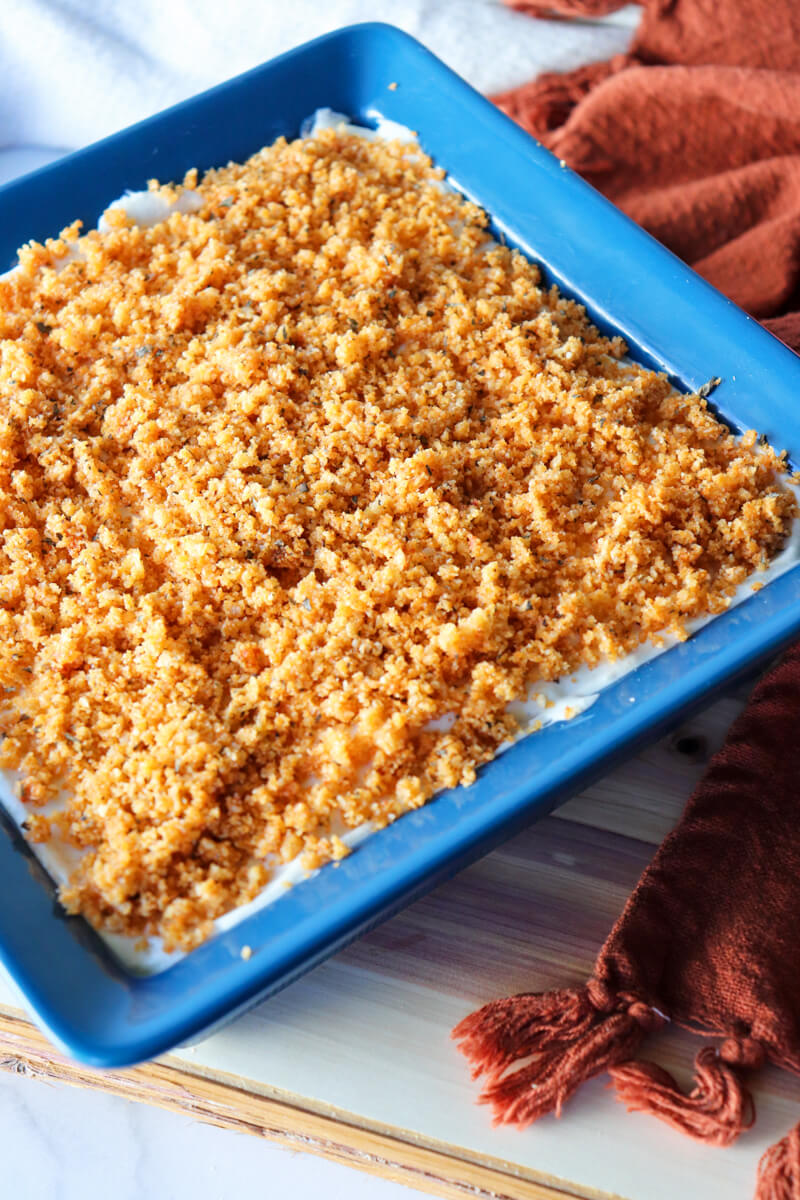 Keto chicken cordon bleu casserole with crispy pork rind topping baked in a blue dish