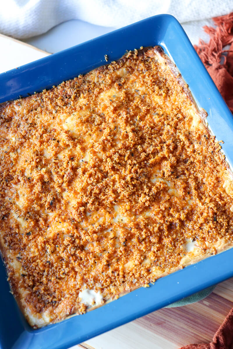 Overhead view of keto chicken cordon bleu casserole with crispy pork rind topping ready to be baked in a blue dish