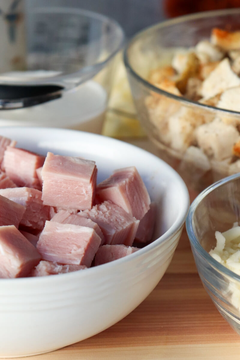 White ceramic bowl of chopped ham surrounded by glass bowls with other ingredients