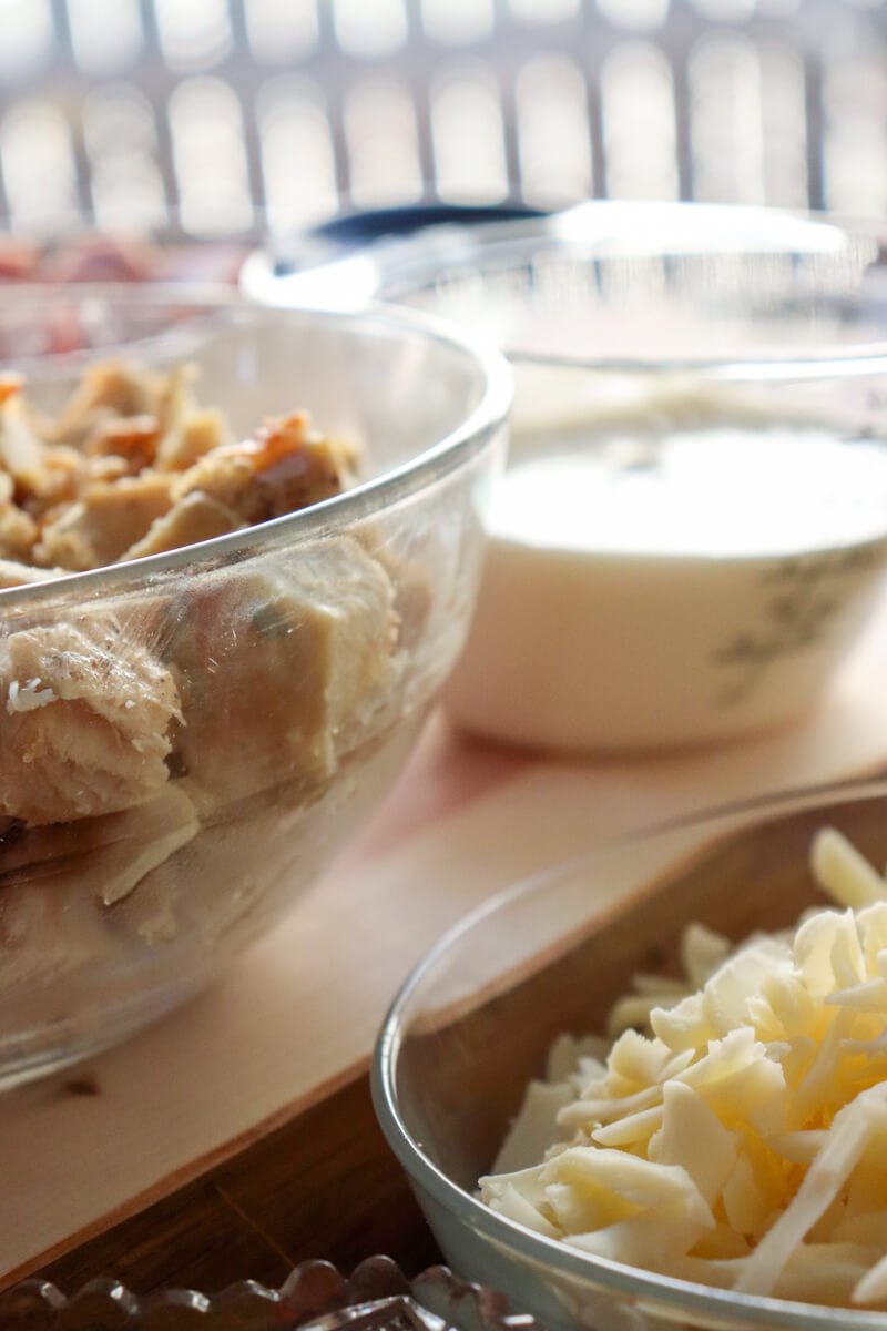 Glass bowls and measuring cup with chicken, cheese, and heavy cream