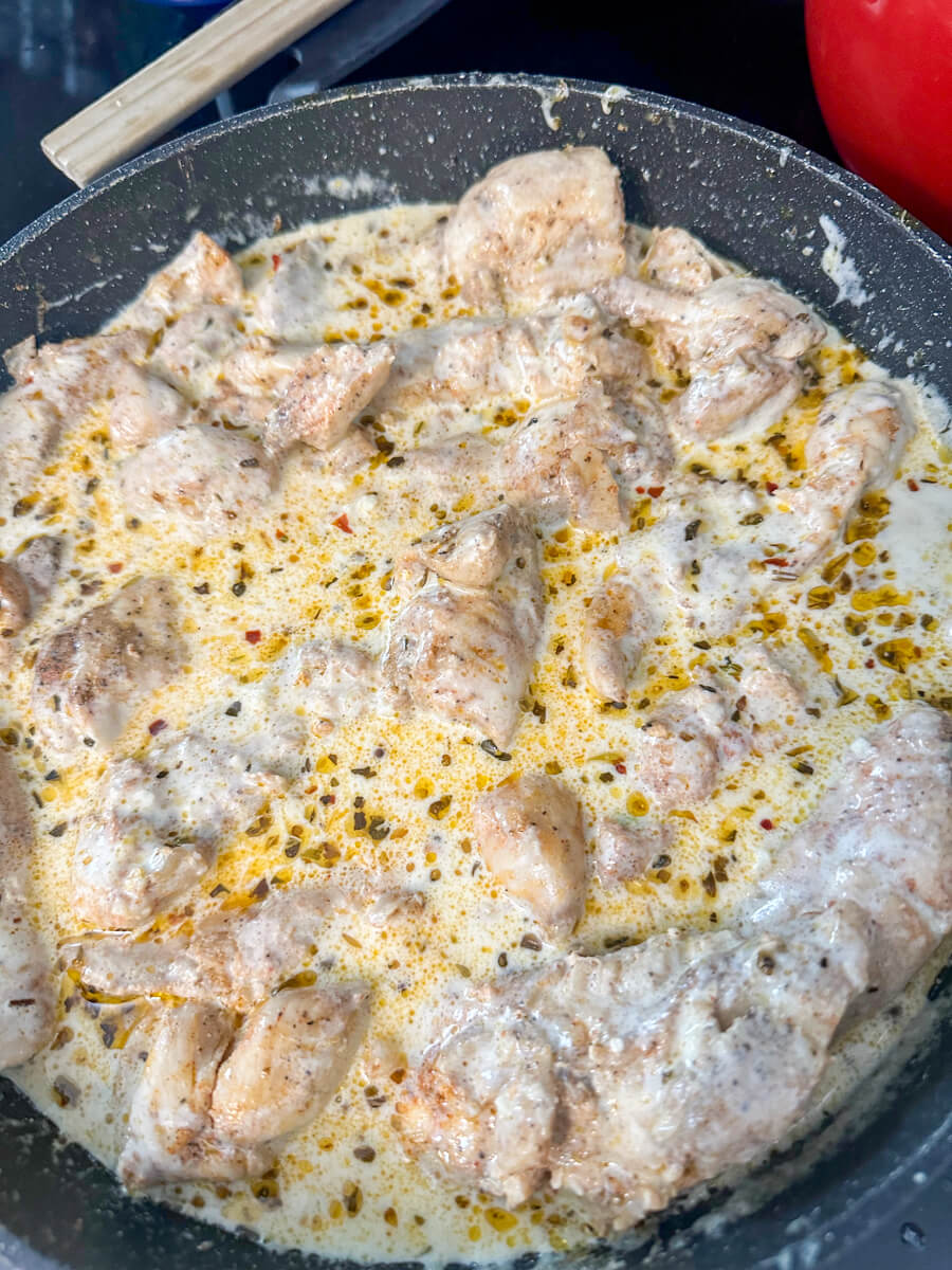 Overhead view of a skillet cooking with creamy lemon garlic chicken in sauce