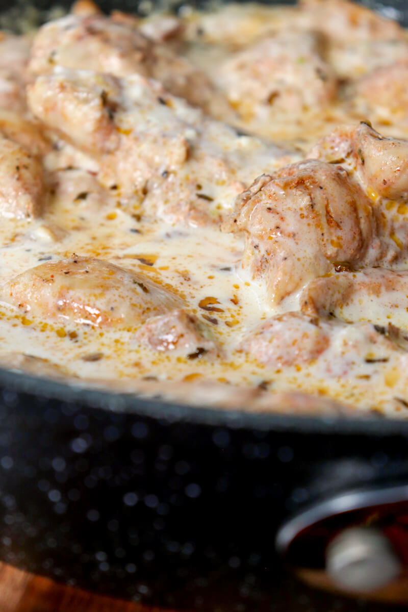 Front close up view of a section of a skillet with creamy lemon garlic chicken in sauce