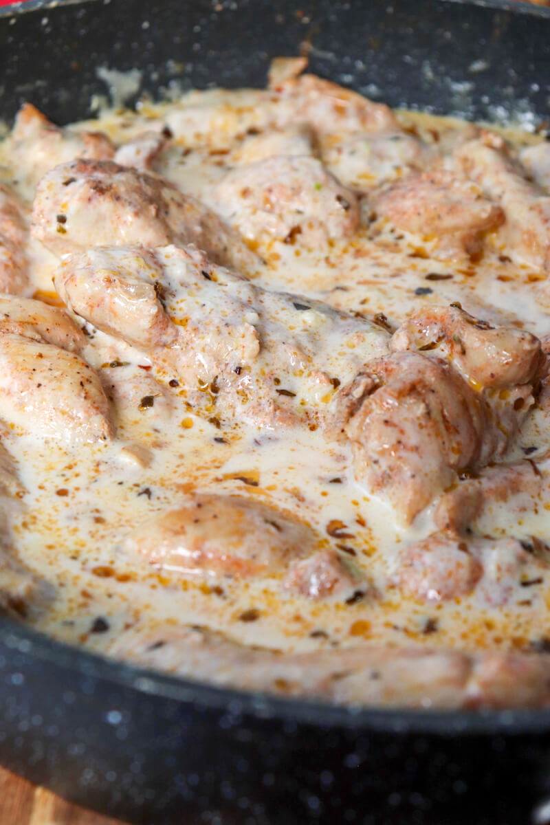 Front view of a section of a skillet with creamy lemon garlic chicken in sauce