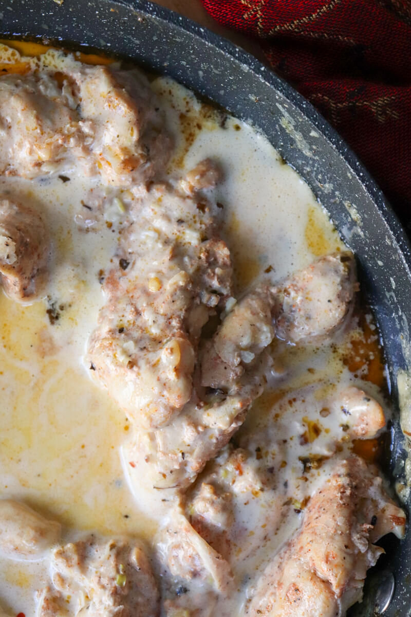 Overhead view of a section of a skillet with creamy lemon garlic chicken in sauce