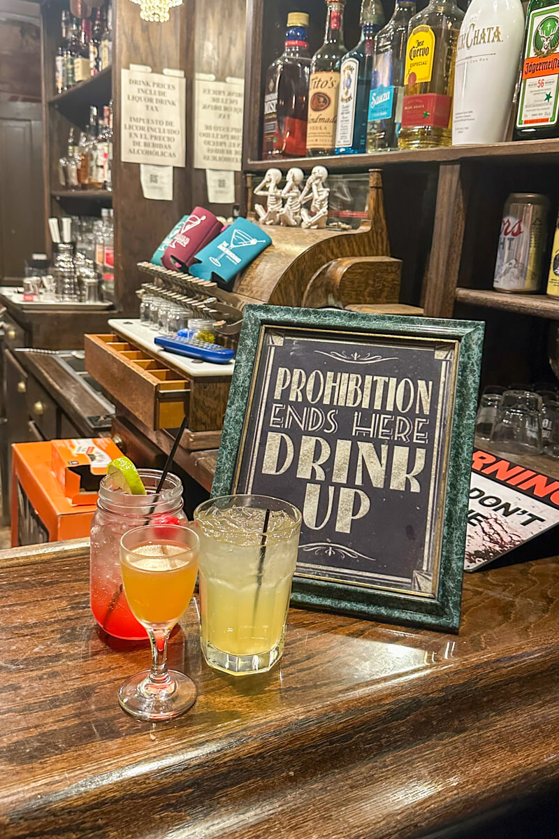 The Underground Speakeasy counter with 3 drinks and a sign that says "Prohibition Ends Here Drink Up".