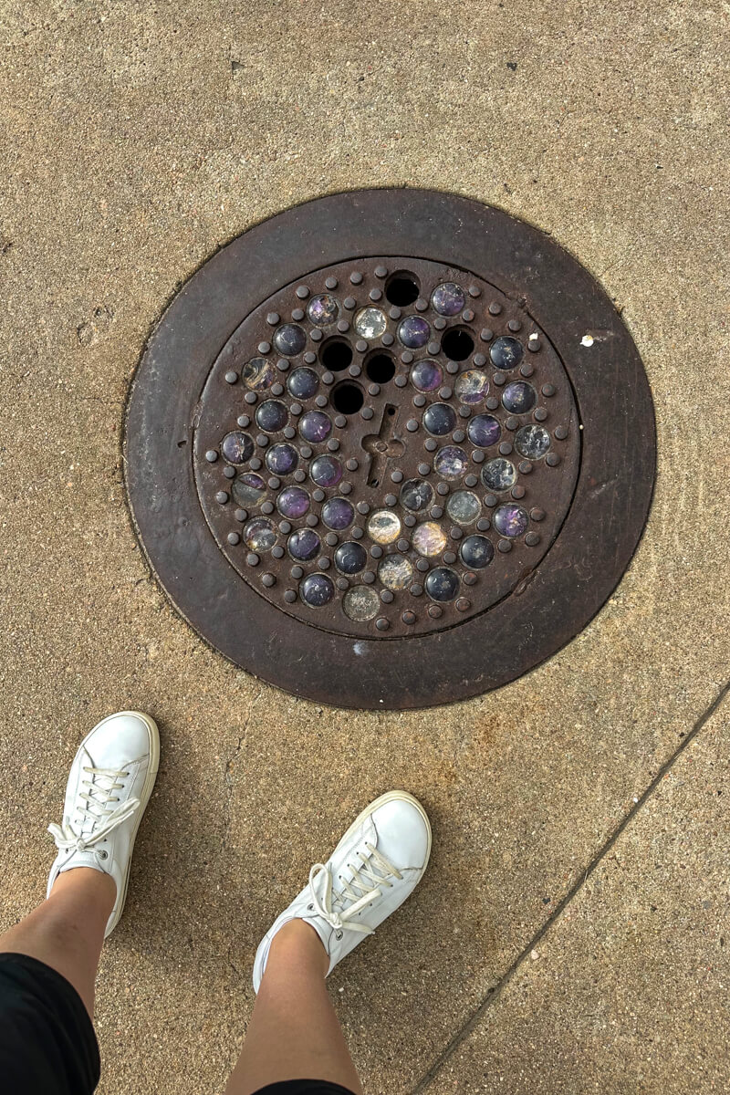 Looking down at a metal circle pothole that leads down to the underground city in Ellinwood Kansas