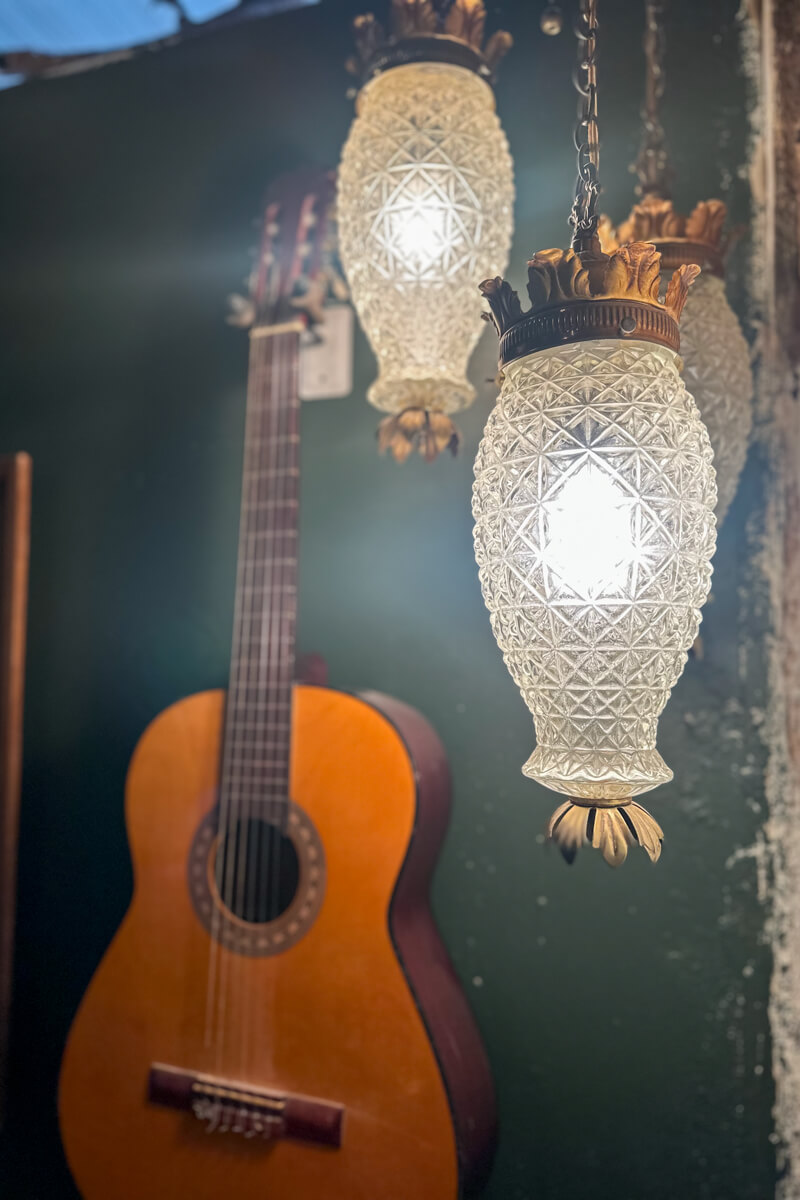 A close up of the jewel green wall with an acoustic guitar and white raindrop shaped lighting