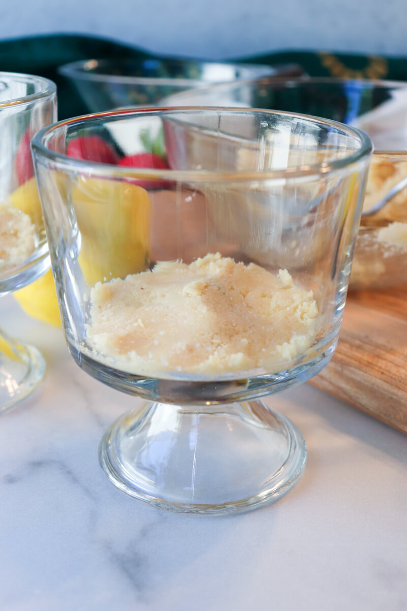 Side view of a small glass serving dish with the almond flour crust pressed into the bottom.