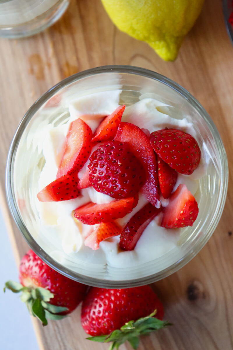 Overhead view of a keto strawberry cheesecake in a clear glass cup with whipped cheesecake filling topped with sliced strawberries.