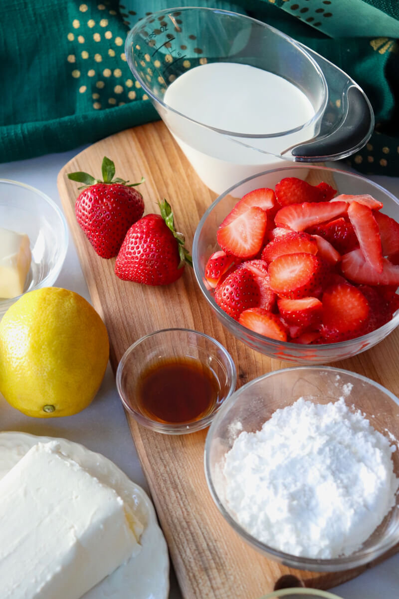 View of the sliced strawberries, cream, sweetener, cream cheese and lemon.