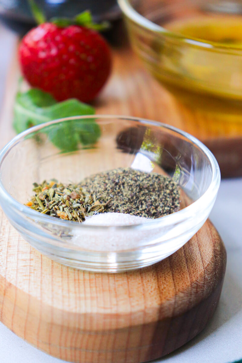 A small glass bowl of Italian seasoning, salt, and pepper