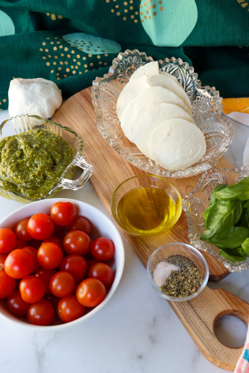 Overhead view of bowls of ingredients in low carb pesto chicken with tomatoes and mozzarella
