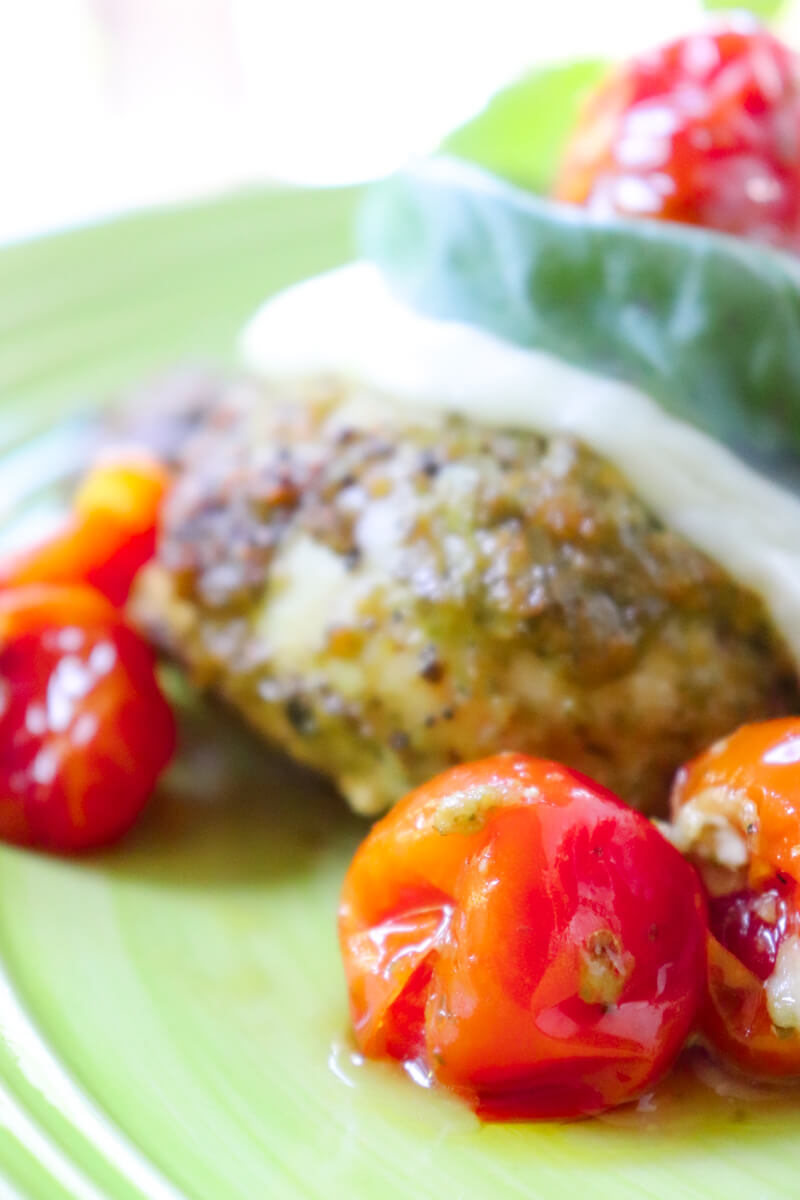 Front close up view of Pesto Chicken with Roasted Tomatoes & Mozzarella on a light green plate with arugula in the background
