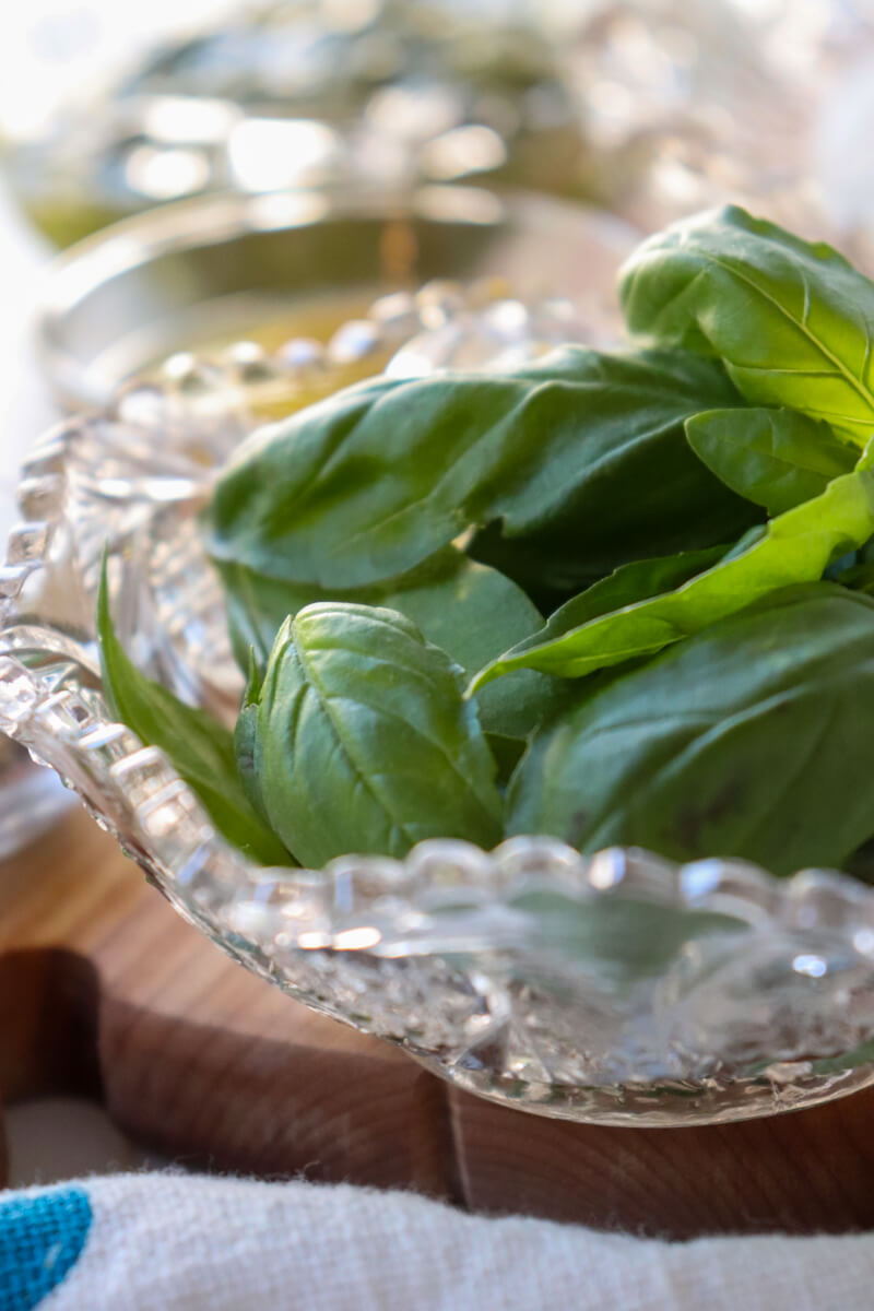 A decorative glass bowl of basil leaves